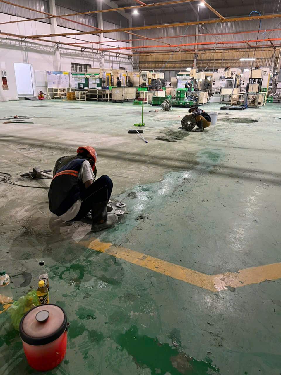 Xử lý bề mặt sàn xưởng trước các bước hoàn thiện công nhân xử lý bề mặt sàn xưởng có lớp phủ màu xanh cũ